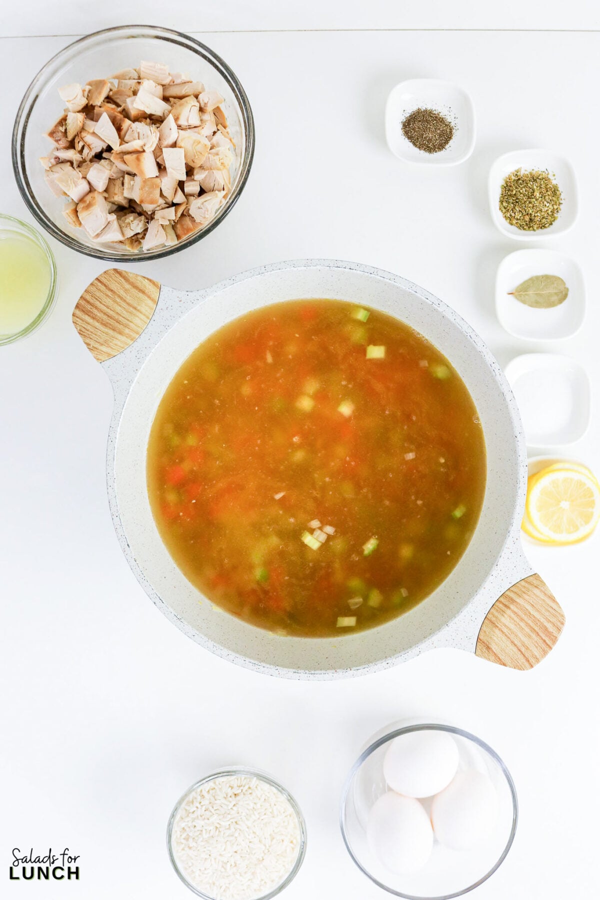 Greek Lemon Chicken and Rice Soup (Easy Avgolemono Recipe) - Greek Lemon Chicken Soup with Rice Recipe 38 Chicken broth with carrots, celery, and onion simmering in a pot, surrounded by shredded chicken, rice, eggs, lemon, and spices.