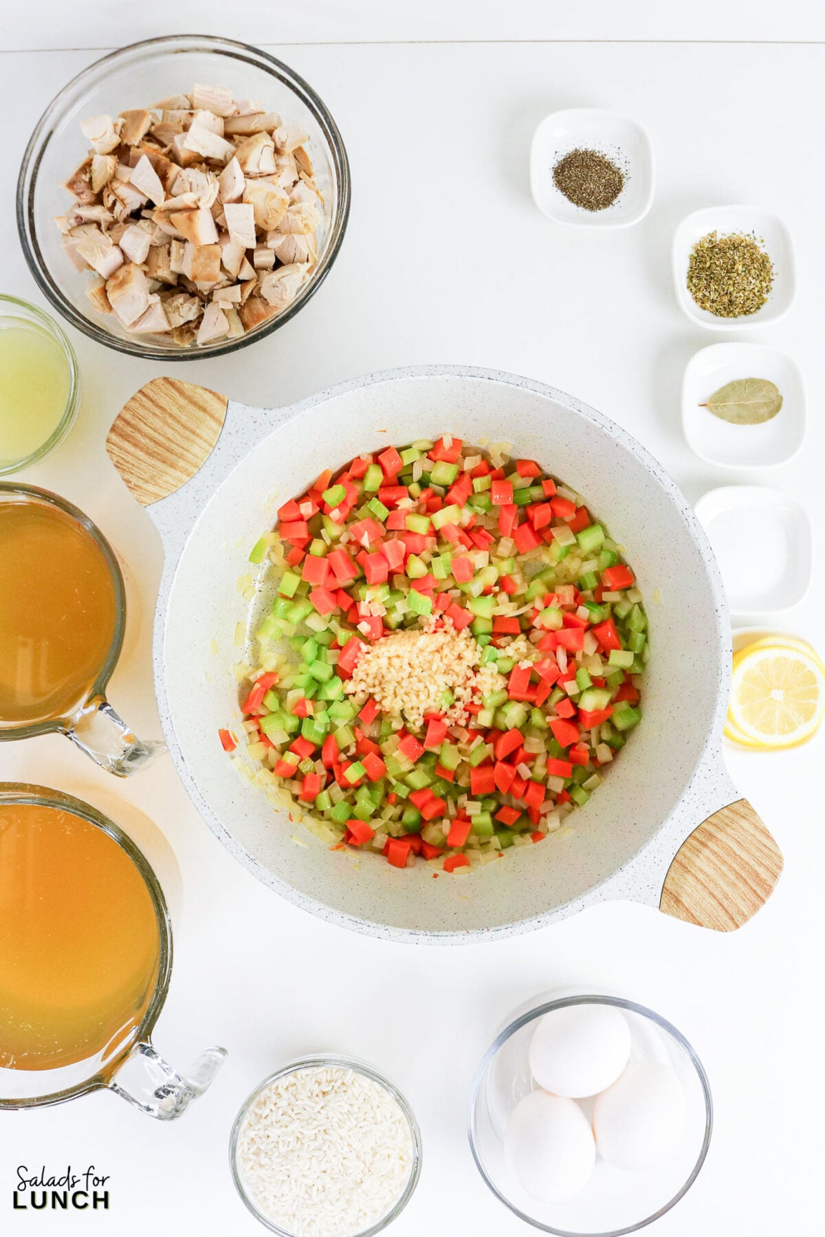 Greek Lemon Chicken and Rice Soup (Easy Avgolemono Recipe) - Greek Lemon Chicken Soup with Rice Recipe 41 Minced garlic added to sautéed diced carrots, celery, and onion in a large pot, surrounded by prepped avgolemono soup ingredients.