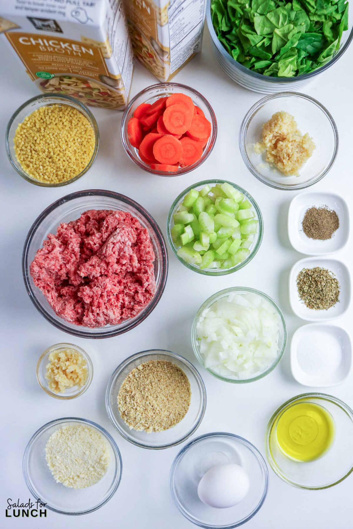Ingredients for Italian wedding soup: ground meat, acini di pepe, carrots, celery, onion, spinach, breadcrumbs, garlic, eggs, olive oil, spices, and chicken broth.
