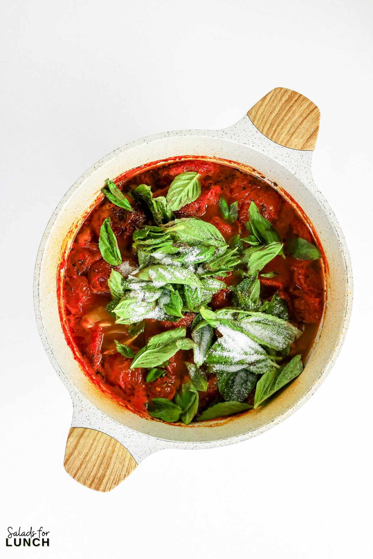 Fresh basil leaves and sugar added to the pot of roasted tomato soup before blending.
