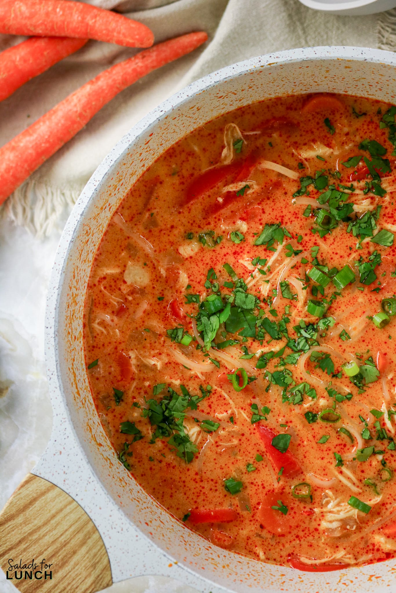 Pot of Thai Coconut Curry Soup with shredded chicken, tomatoes, and cilantro, garnished with parsley.