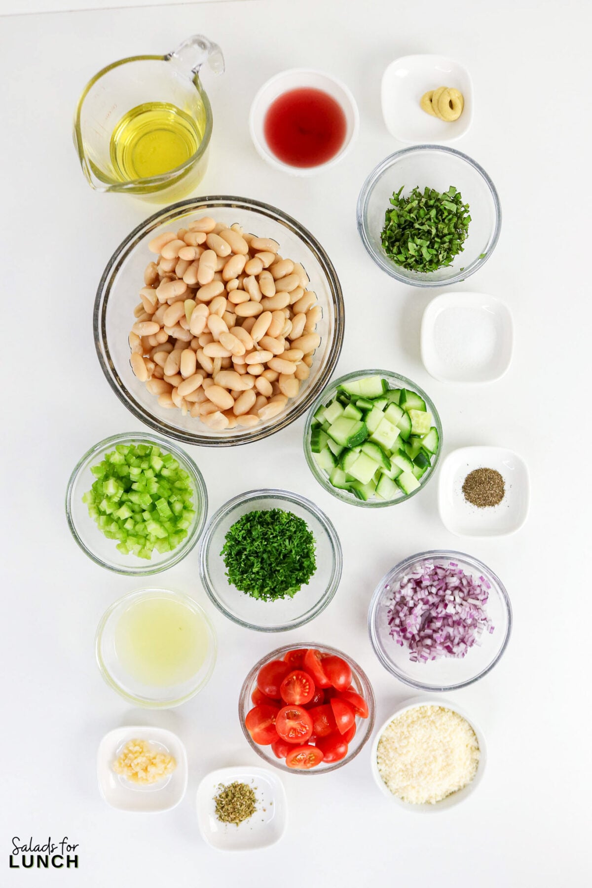 Easy Tuscan Bean Salad - Tuscan Bean Salad Ingredients Tuscan white bean salad ingredients including cannellini beans, cherry tomatoes, cucumber, celery, red onion, parsley, olive oil, and seasonings in individual bowls.