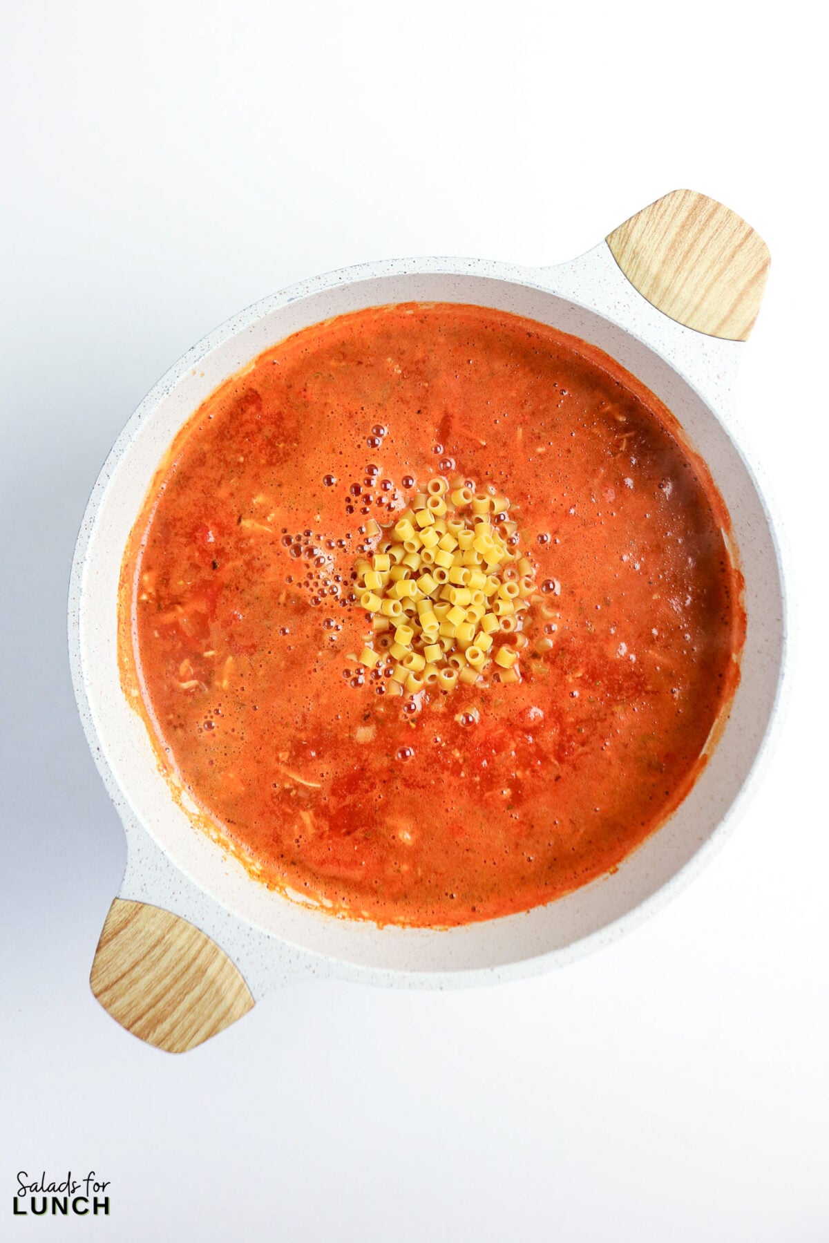 One-Pot Chicken Parmesan Soup - Chicken Parmesan Soup Process 08 Ditalini pasta added to the tomato broth in a pot before simmering into the soup.