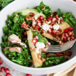 Easy Greek Salad Dressing - Kale Pomegranate Salad Hero 01 Bowl of kale salad topped with sliced apples, pomegranate seeds, goat cheese, red onion, and chopped pecans.