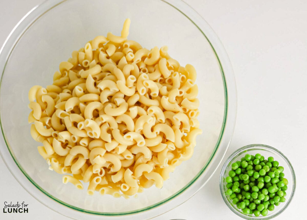 Creamy Tuna Macaroni Salad - Tuna Macaroni Salad Hero 17 Bowl of cooked elbow macaroni next to a small bowl of green peas.