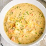 Bowl of creamy cheeseburger soup with ground beef, carrots, shredded cheddar cheese, and parsley.