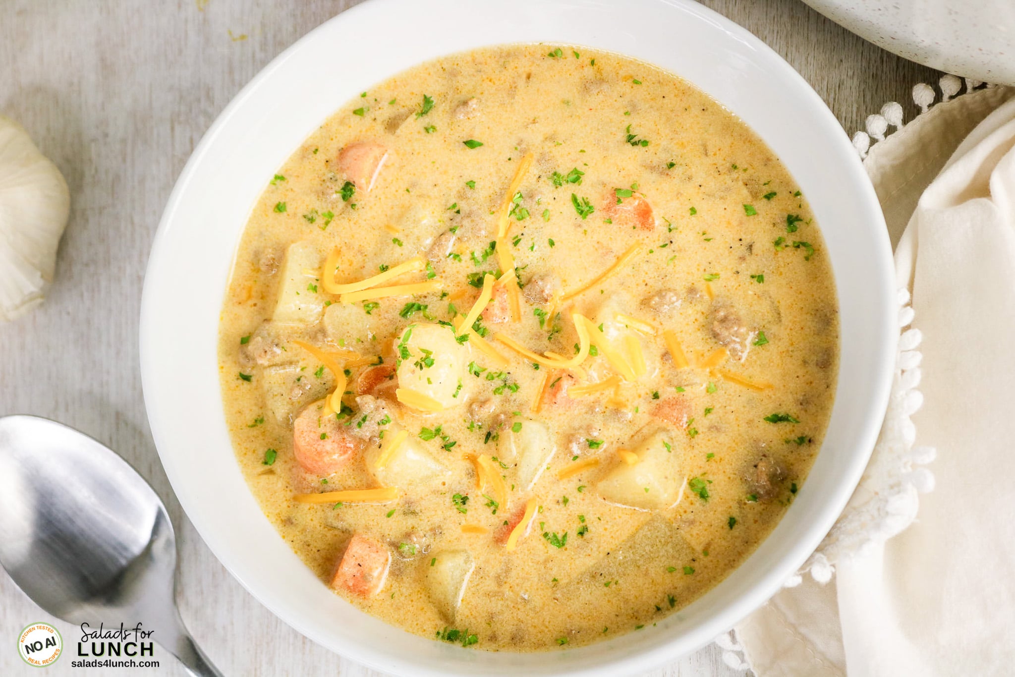 Easy Cheeseburger Soup Recipe - Cheeseburger Soup Recipe Hero 12 Bowl of creamy cheeseburger soup with ground beef, carrots, shredded cheddar cheese, and parsley.