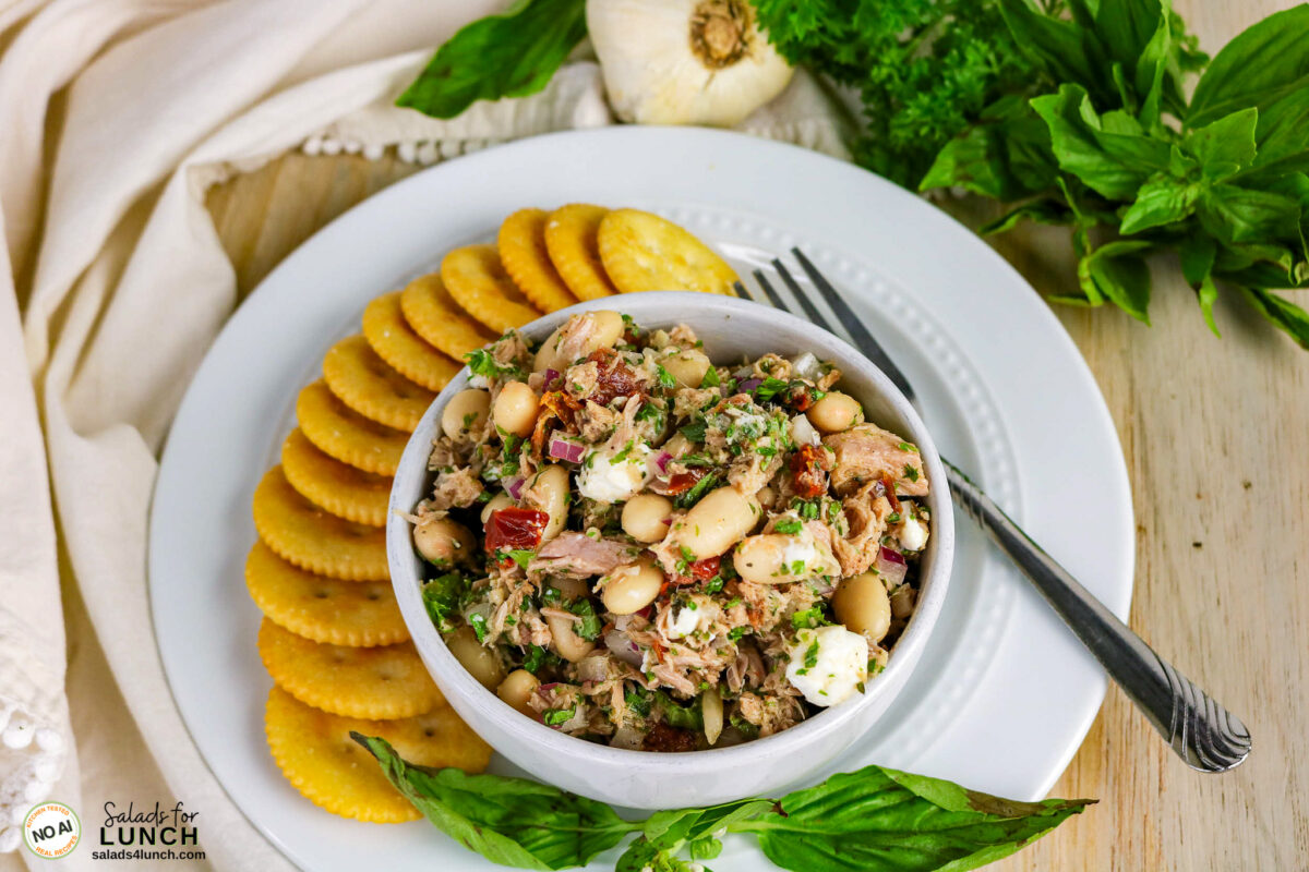 Tuscan Tuna Salad - Tuscan Tuna Salad Process 01 Bowl of tuscan tuna and white bean salad with sun-dried tomatoes, feta, and herbs, served with round crackers.