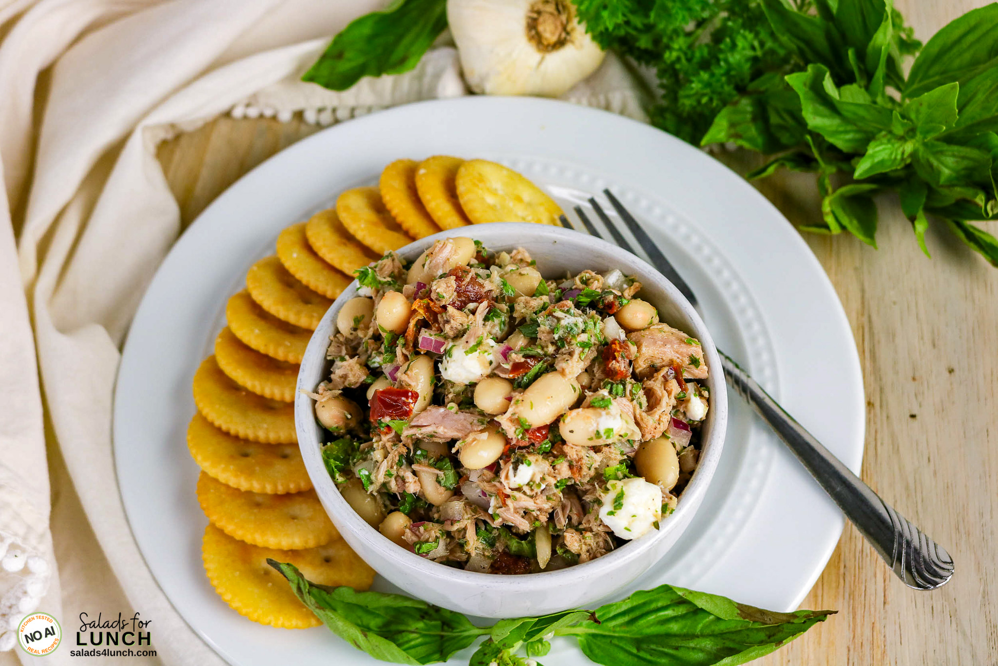 Tuscan Tuna Salad - Tuscan Tuna Salad Process 01 Bowl of tuscan tuna and white bean salad with sun-dried tomatoes, feta, and herbs, served with round crackers.