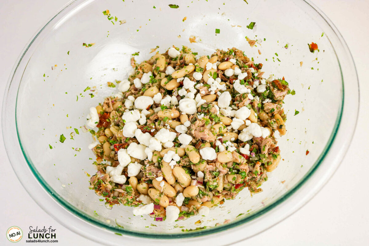 Tuscan Tuna Salad - Tuscan Tuna Salad Process 05 Glass bowl of tuna and white bean salad topped with crumbled goat cheese, herbs, and red onion.